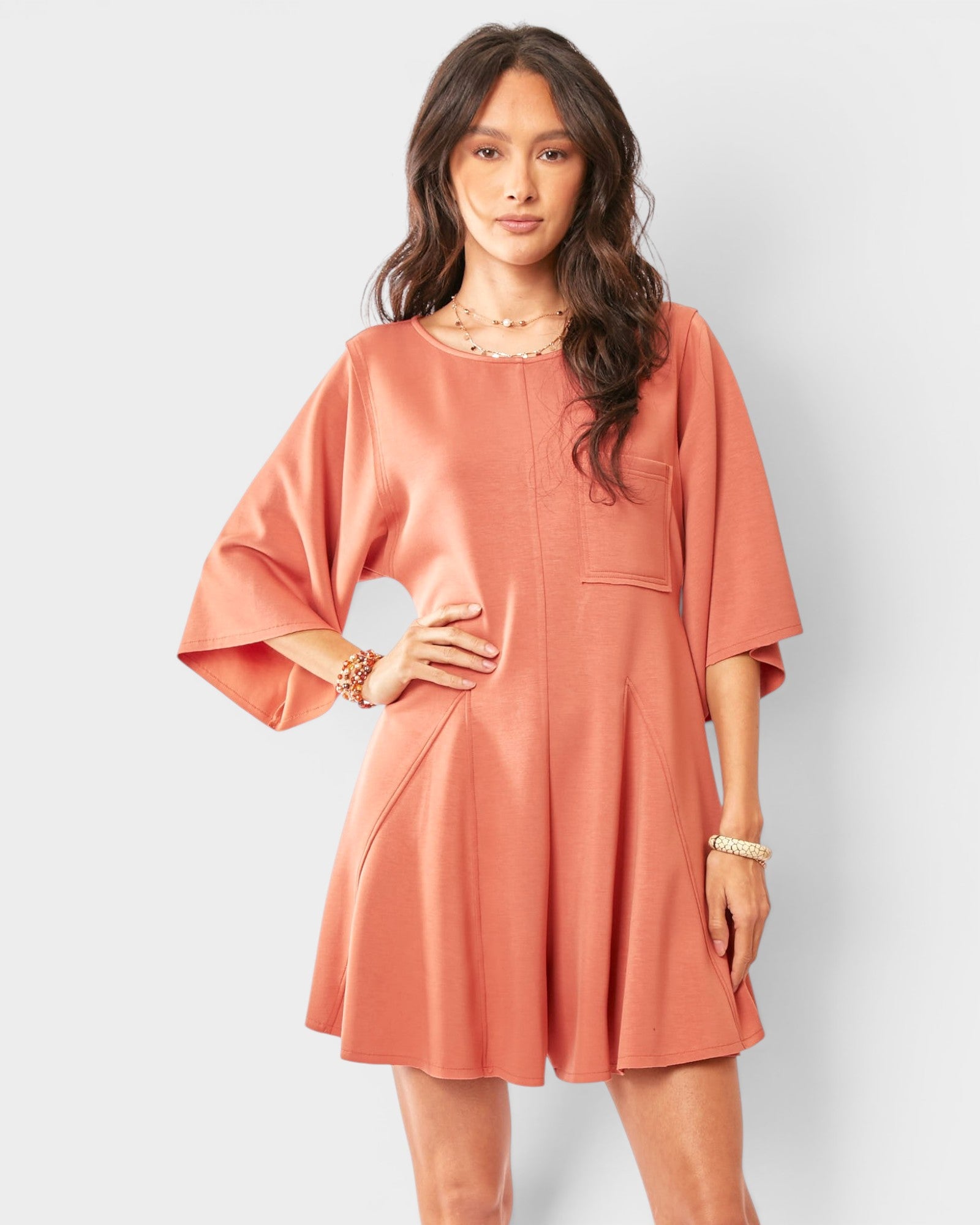 Woman wearing a peach-colored romper against a white background