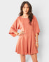 Woman wearing a peach-colored romper against a white background