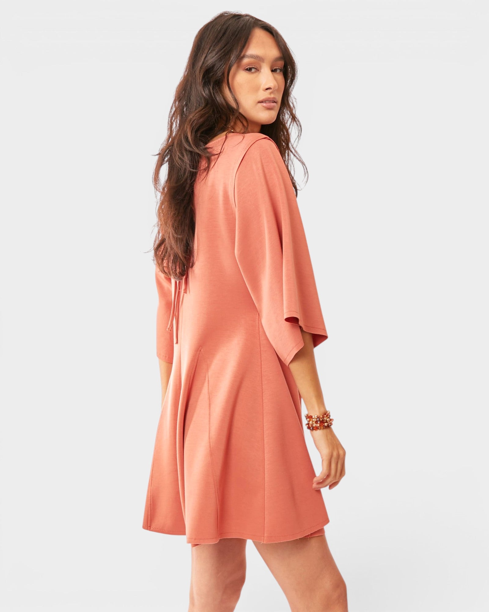 Woman wearing a peach-colored romper against a white background