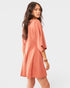 Woman wearing a peach-colored romper against a white background