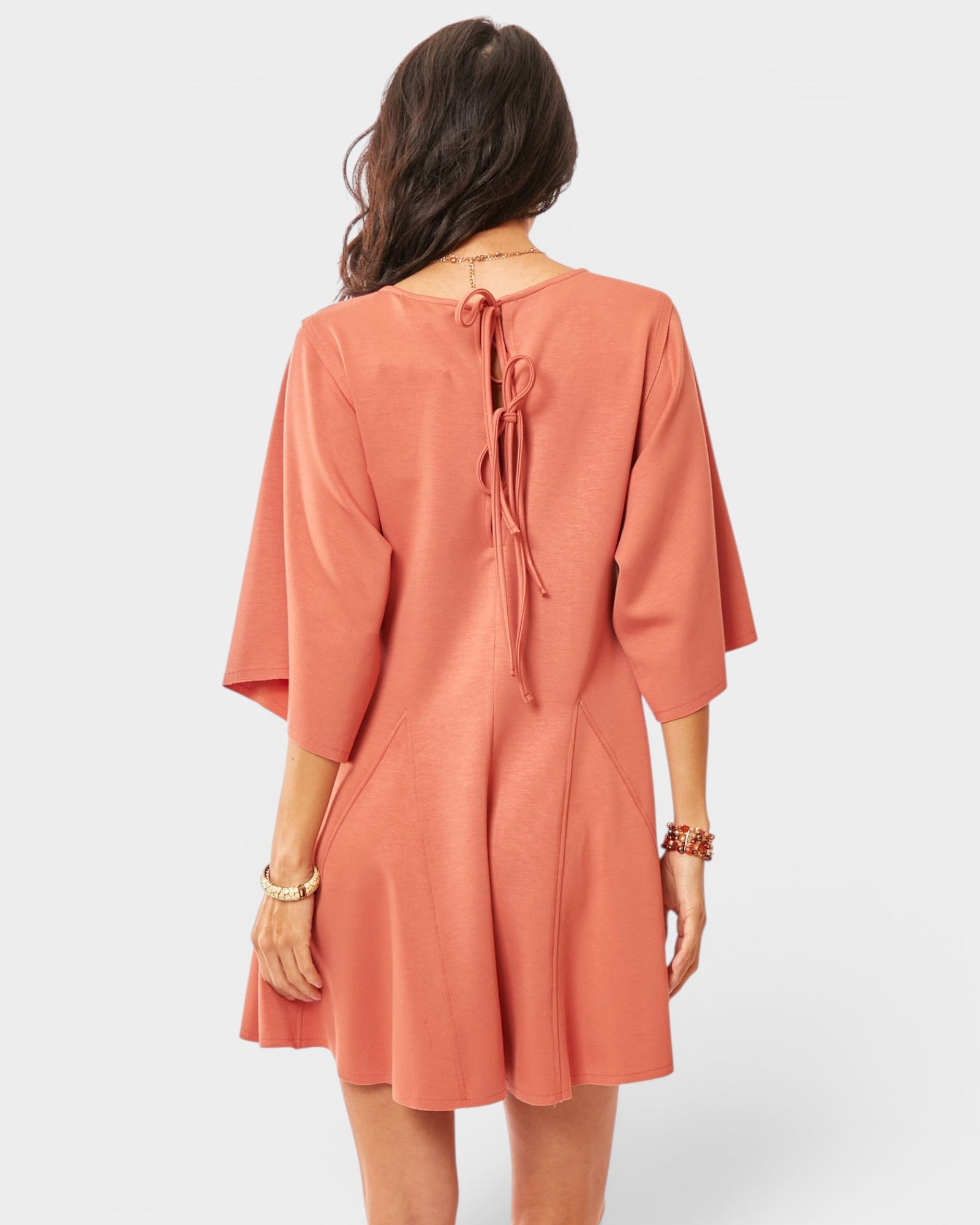 Woman wearing a coral romper with a plain background