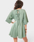 Woman wearing a light green romper with a tie-back detail on a white background
