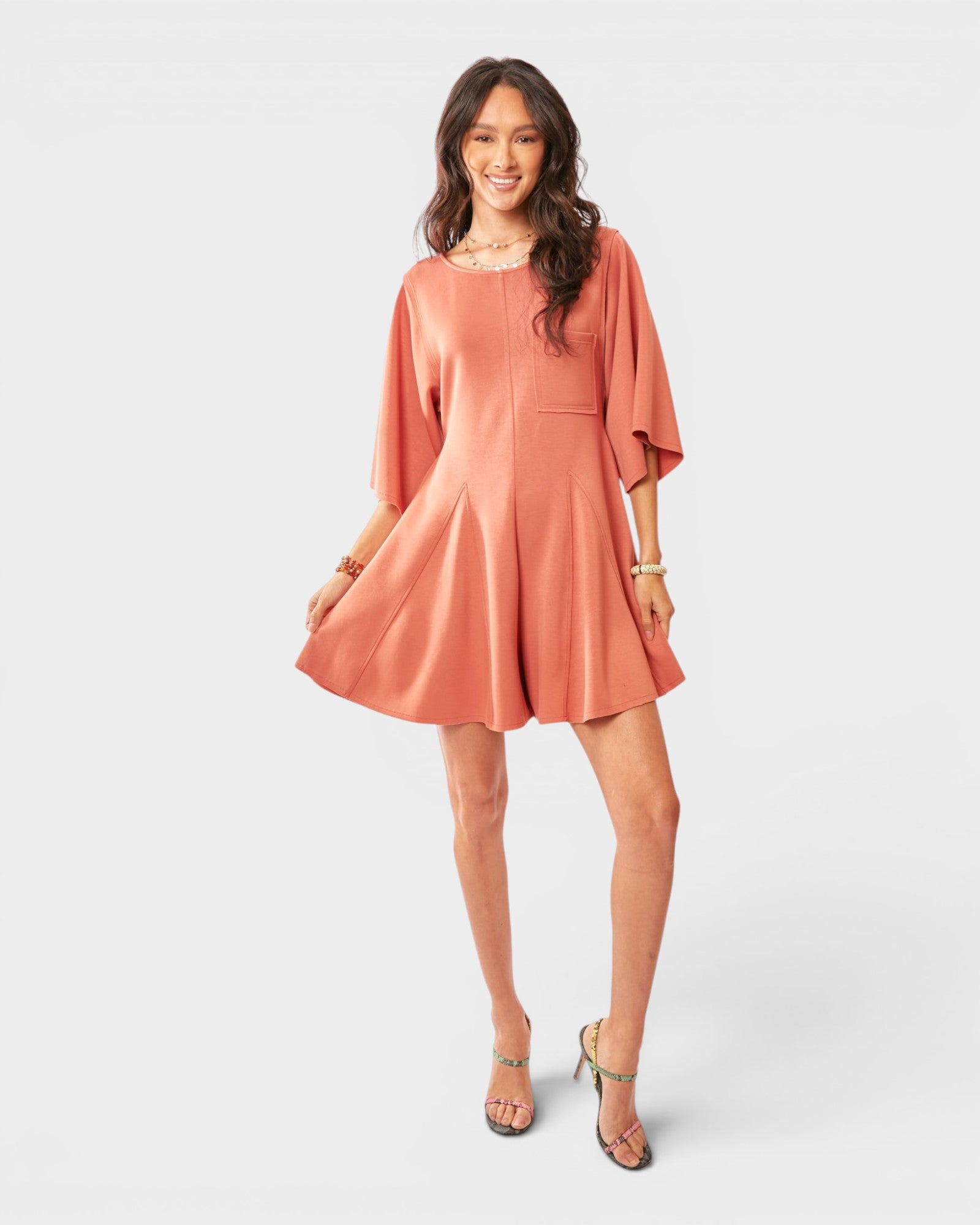 Woman wearing a peach-colored romper against a white background