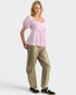 Woman wearing a pink top and beige pants on a white background