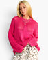 A woman wearing a bright pink open-knit sweater with a star pattern and a leopard-print skirt, photographed against a plain light background.