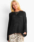A woman wearing a black knit sweater with a large star-shaped cutout pattern on the front, paired with leopard-print pants, against a plain light gray background.