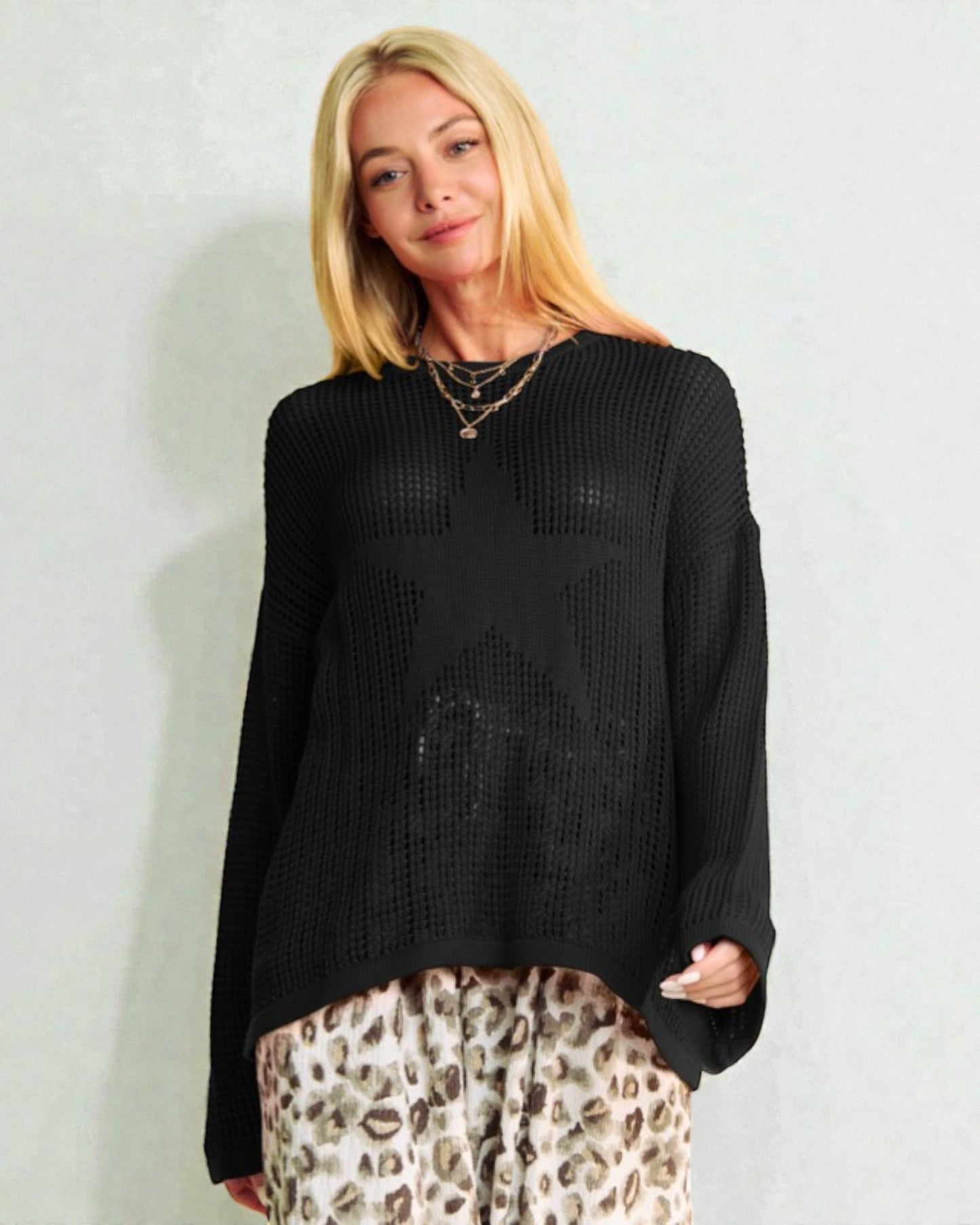 Woman wearing a black sweater and leopard print pants against a light background