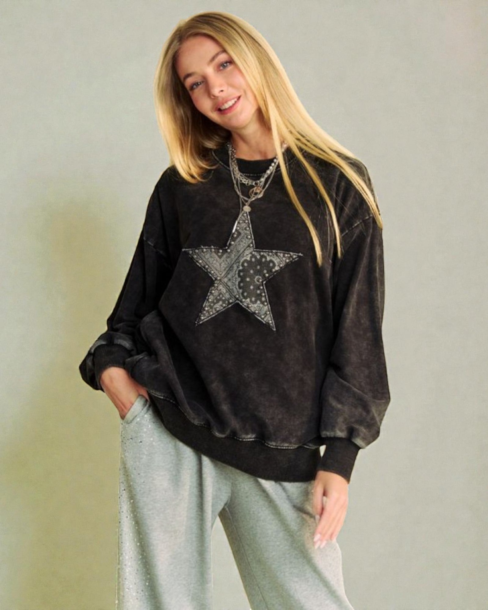 Woman wearing a black sweatshirt with a star design on a plain background