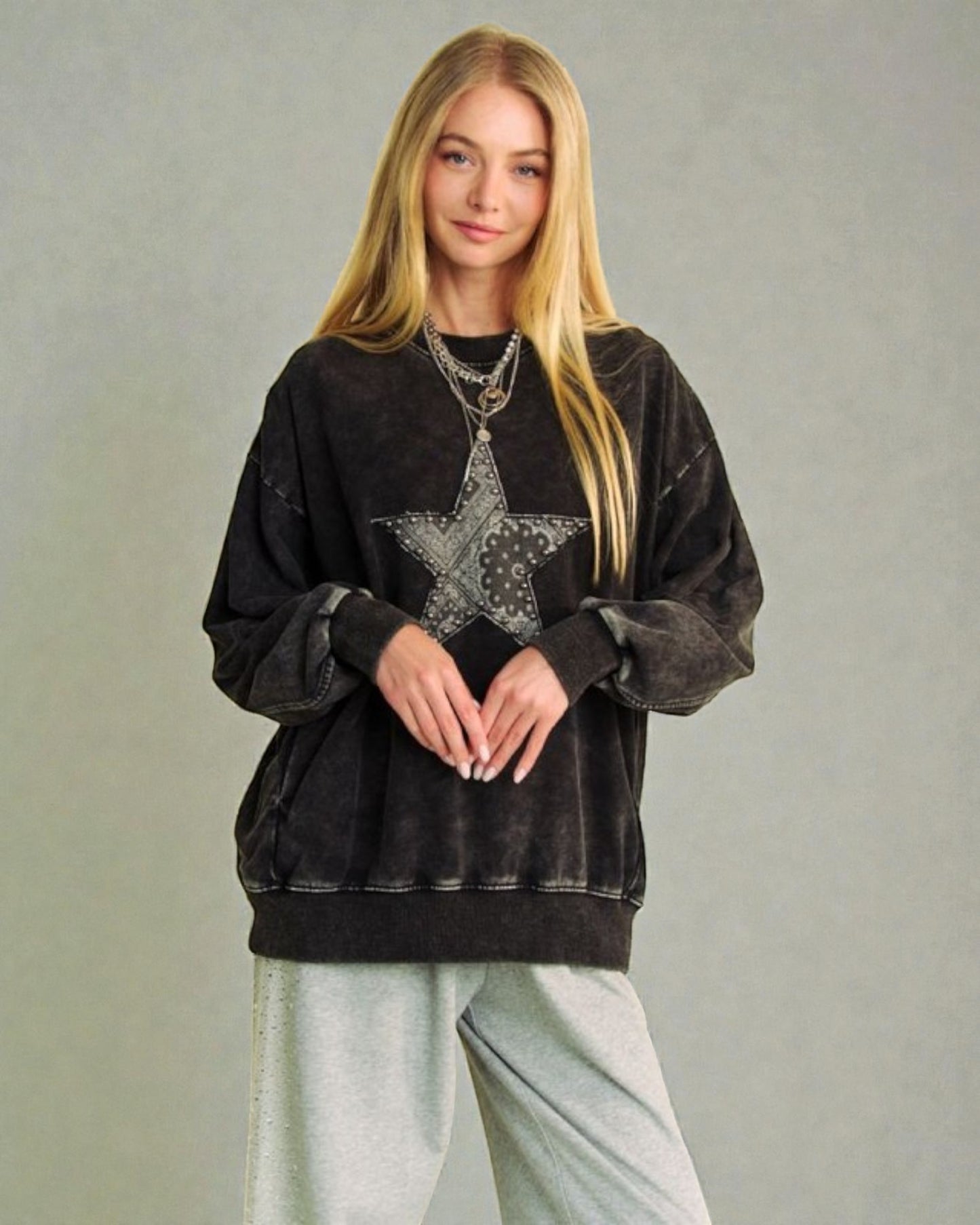 Woman wearing a black sweatshirt with a star design on a plain background