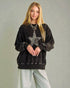 Woman wearing a black sweatshirt with a star design on a plain background