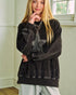 Person wearing a black oversized sweatshirt with a decorative front panel indoors.