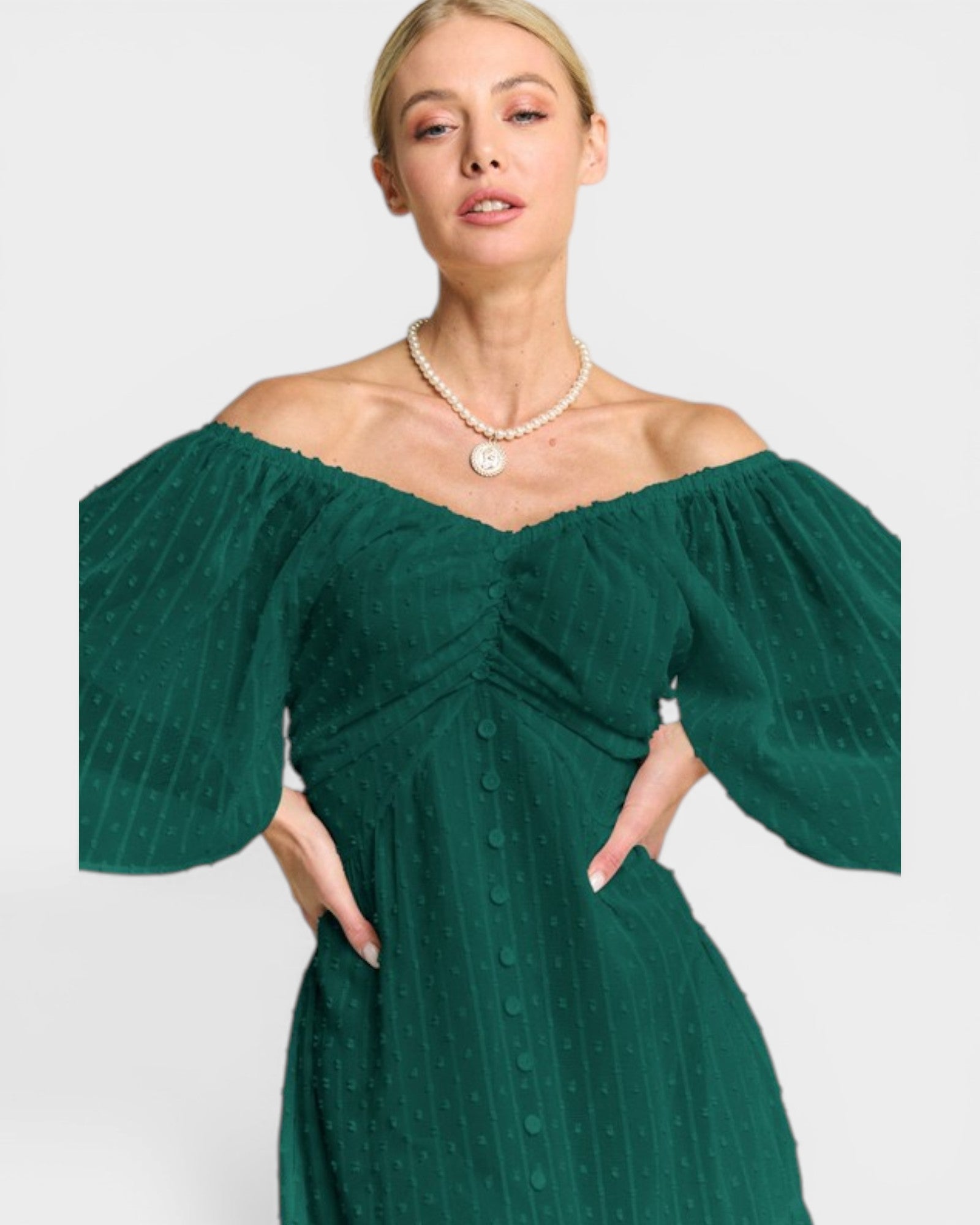 Woman wearing a green off-shoulder dress with a plain background