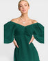 Woman wearing a green off-shoulder dress with a plain background