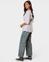 Woman wearing a white blouse with ruffles and blue jeans on a white background
