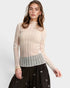 Woman wearing a sheer beige top with a striped bottom on a white background