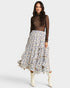 Woman wearing a floral skirt and sheer top on a white background