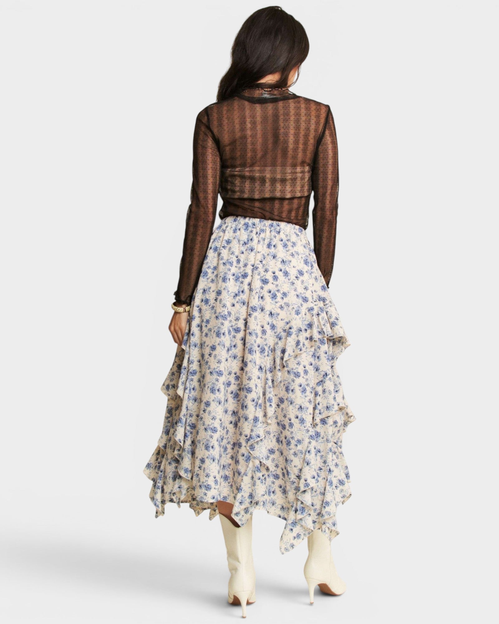 Woman wearing a floral skirt and sheer top on a white background