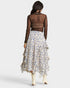 Woman wearing a floral skirt and sheer top on a white background