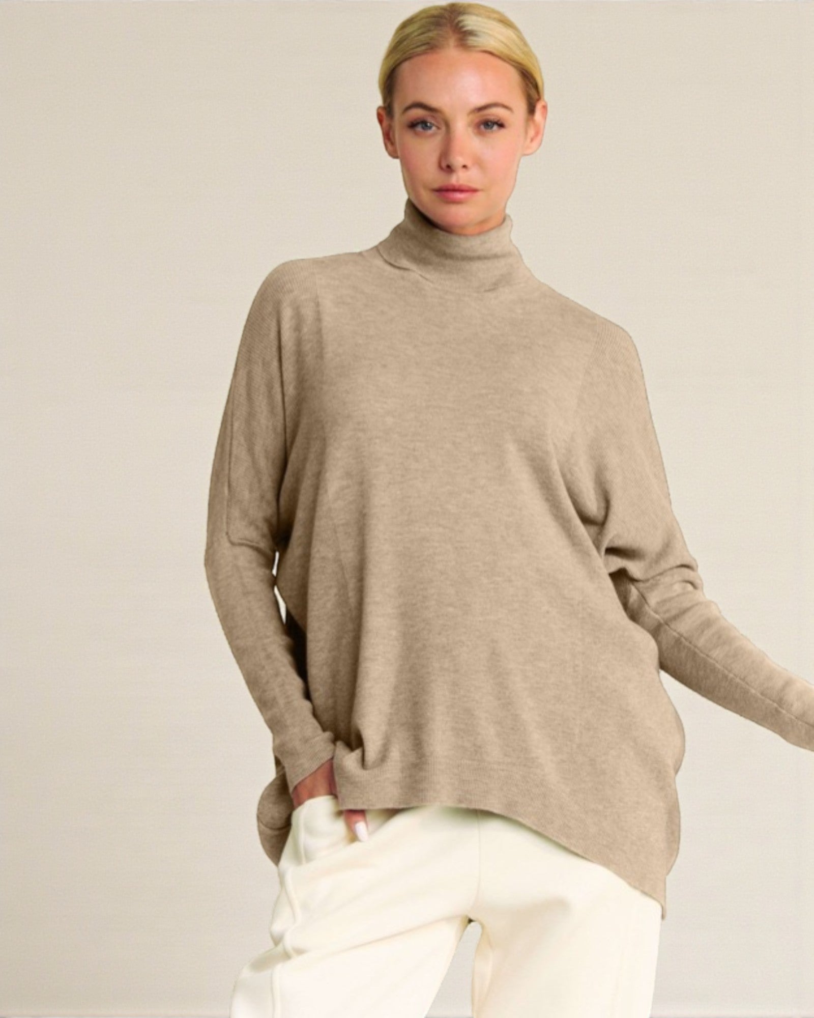 Woman wearing a beige turtleneck sweater against a plain background