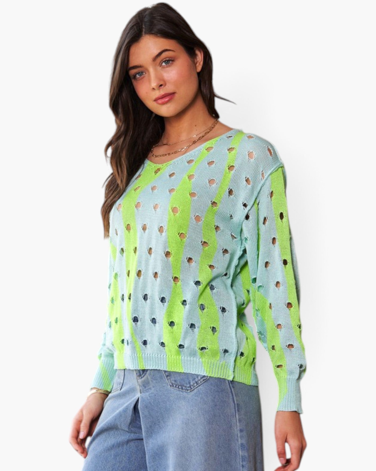A woman modeling a light blue knit sweater with bright lime green vertical stripes and small cutout details, paired with light blue jeans against a plain white background.