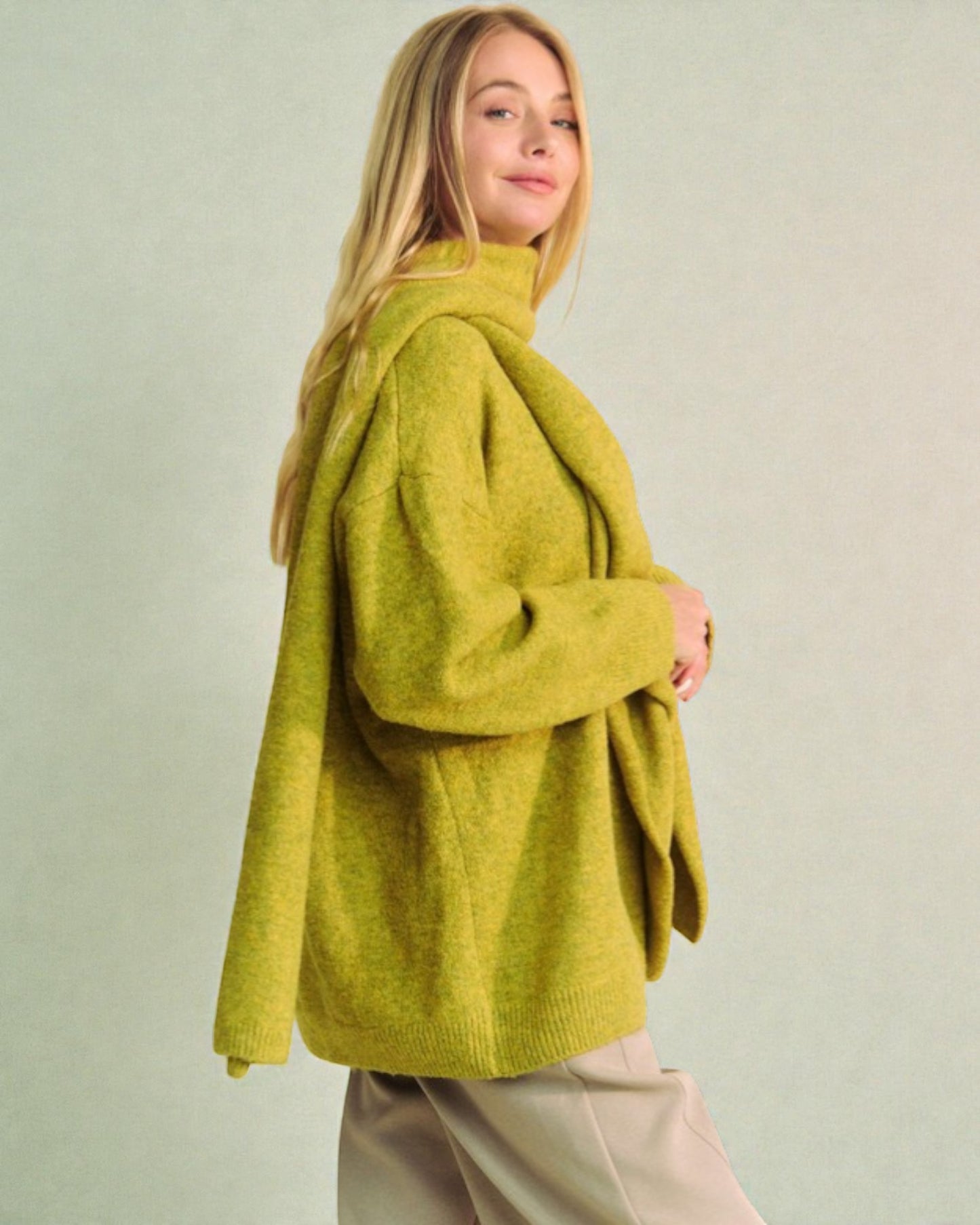 Woman wearing a green sweater against a plain background