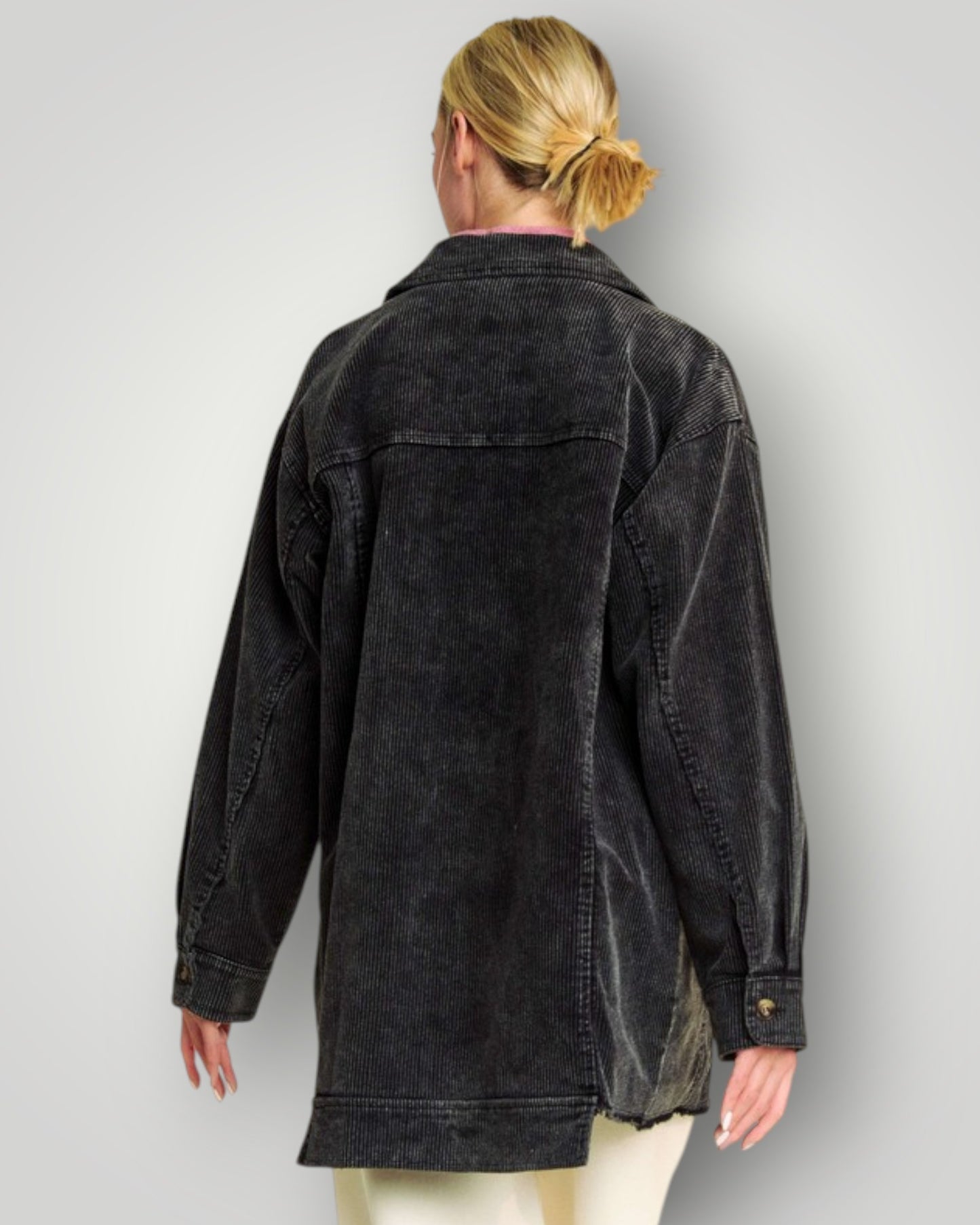 Person wearing a black denim jacket on a plain background