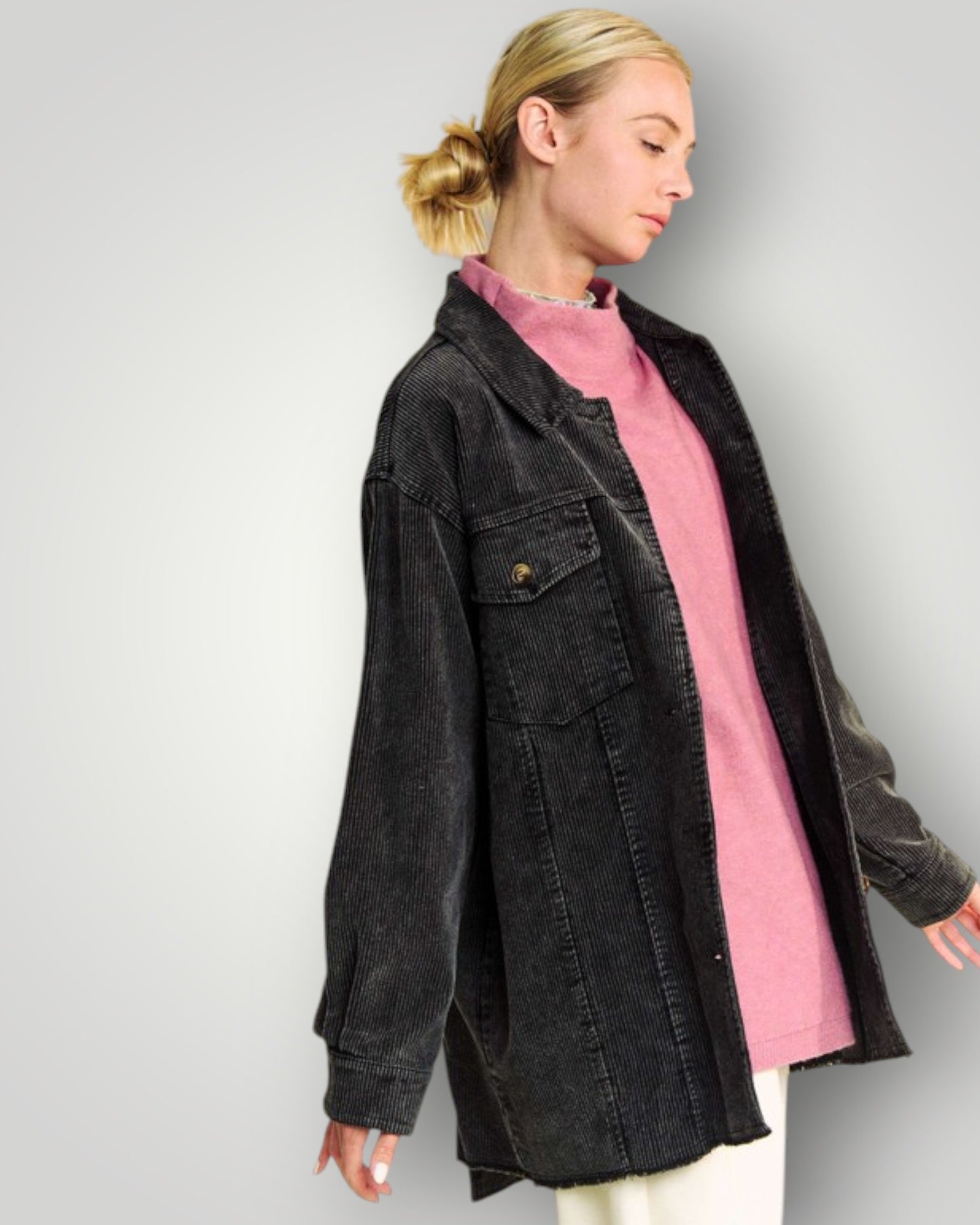 Person wearing a black jacket over a pink shirt on a plain background