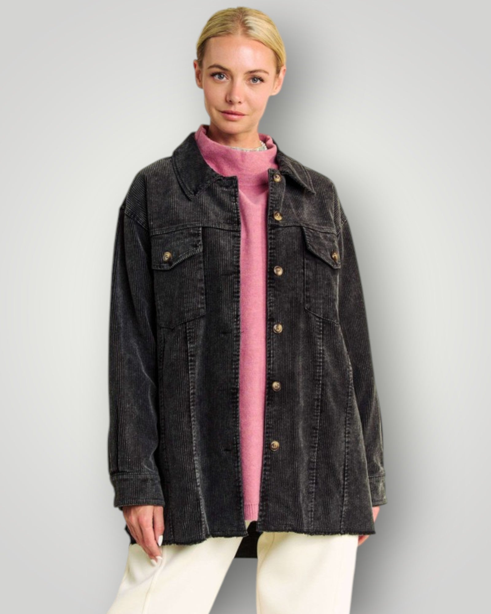 Woman wearing a black denim jacket over a pink shirt on a gray background