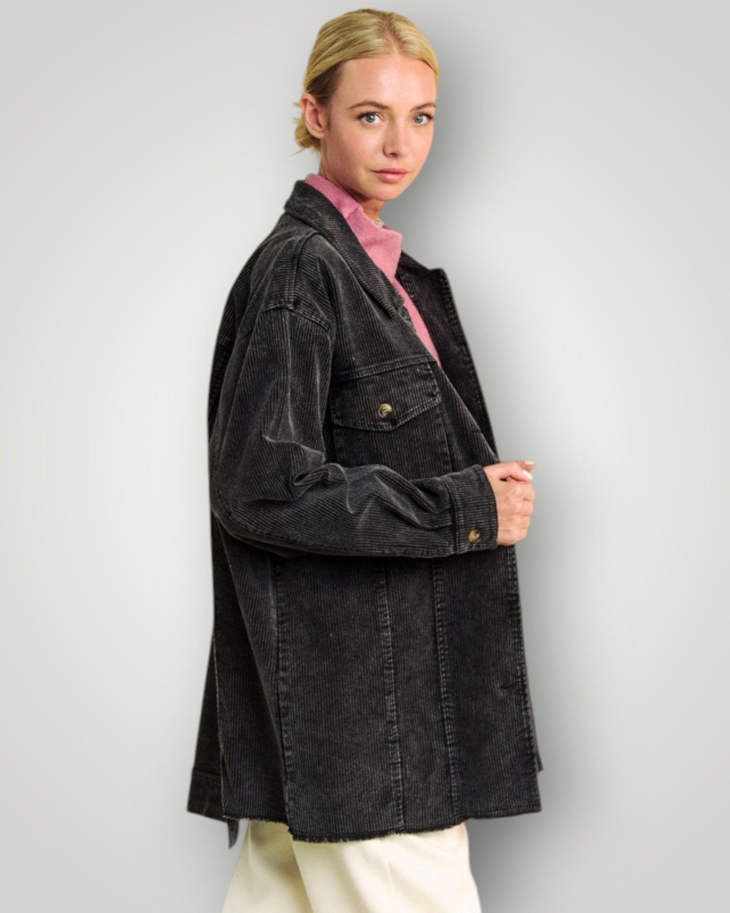 Person wearing a black jacket over a pink shirt on a plain background