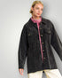 Woman wearing a black jacket over a pink shirt on a gray background
