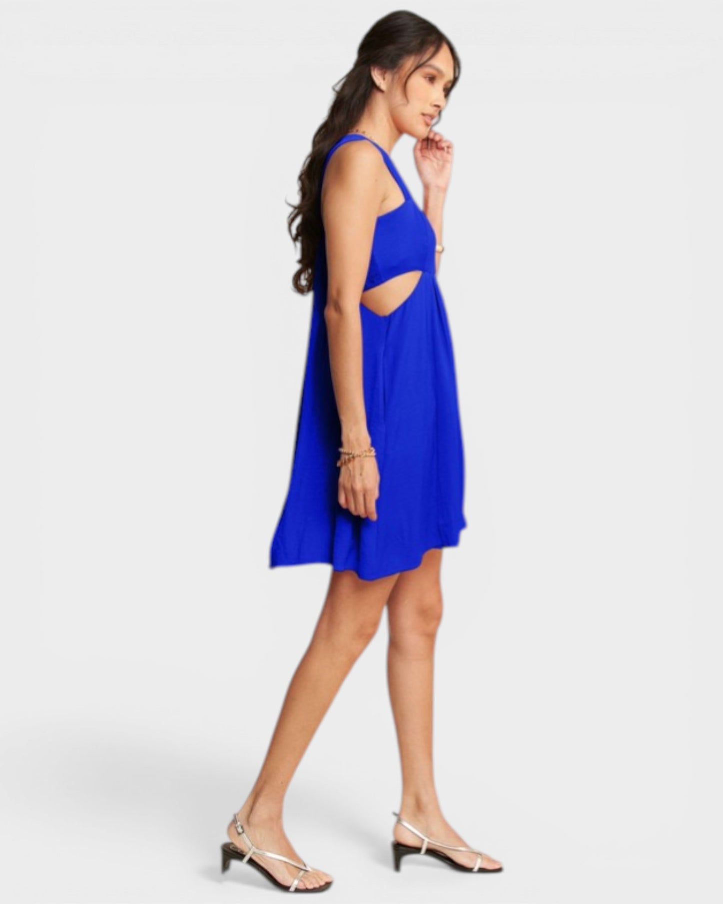Woman wearing a blue dress with cut-out design on a white background