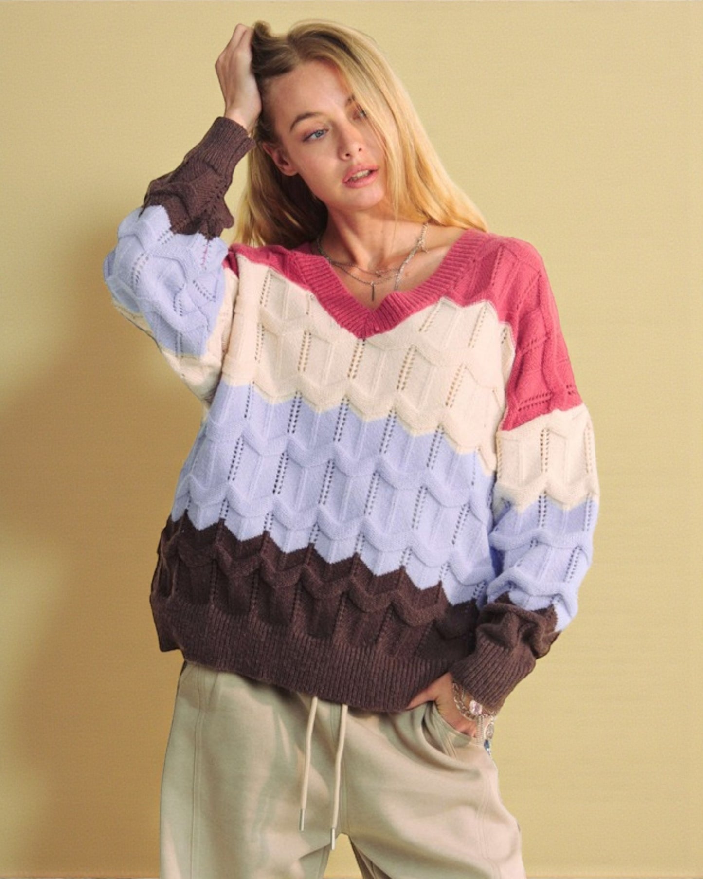 Woman wearing a colorful sweater with a patterned hem against a beige background