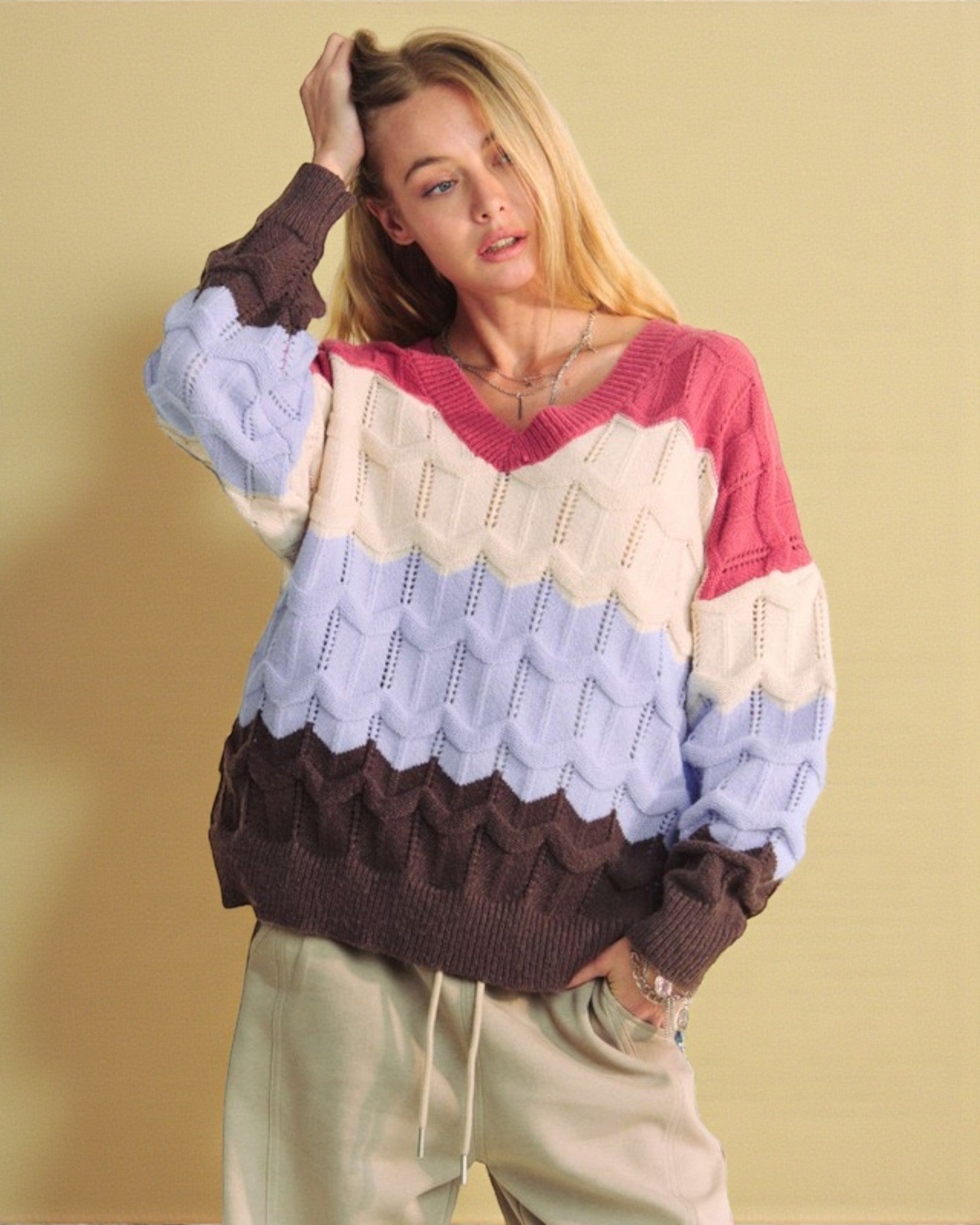 Woman wearing a colorful sweater with a patterned hem against a beige background