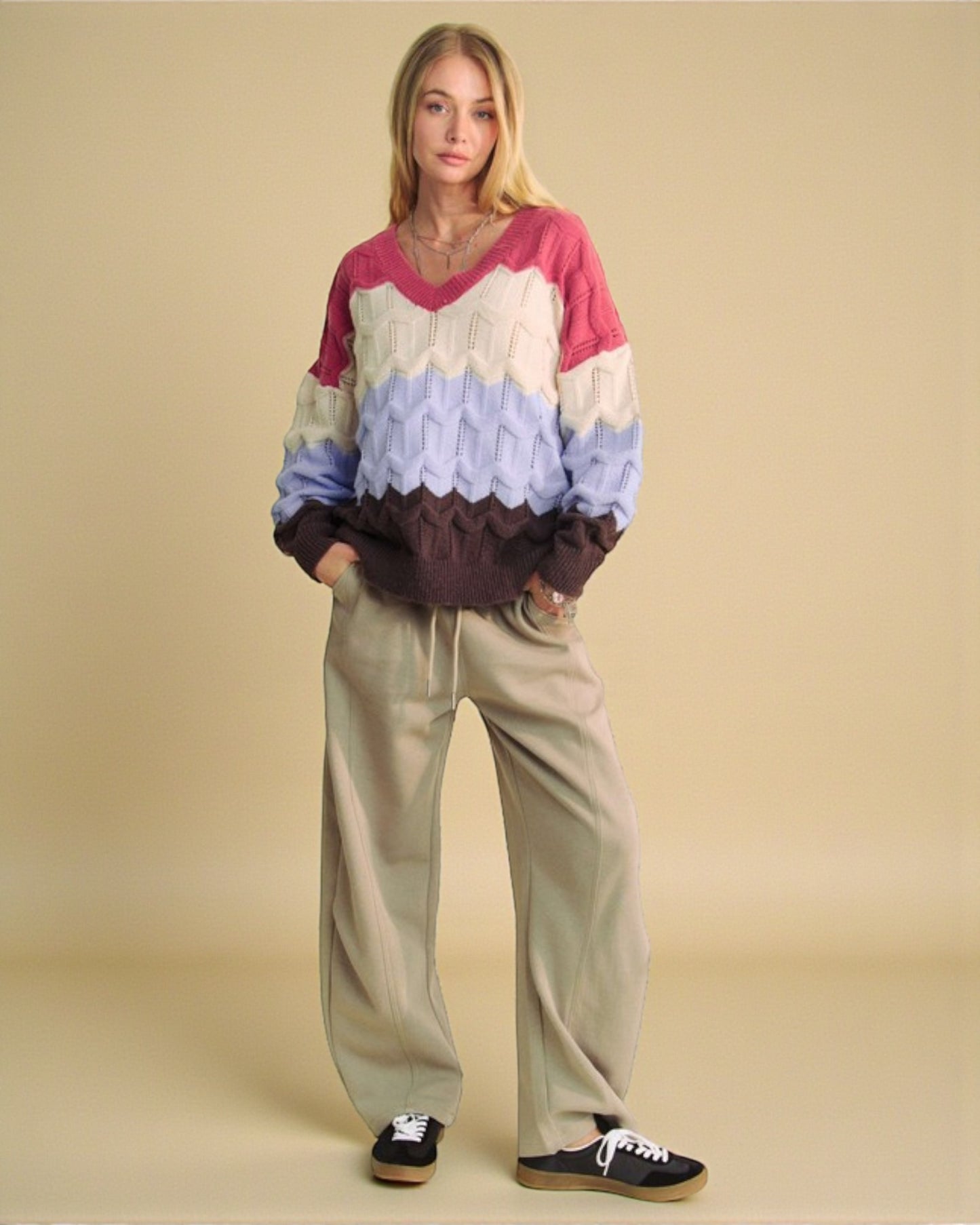 Woman wearing a colorful sweater and beige pants on a beige background