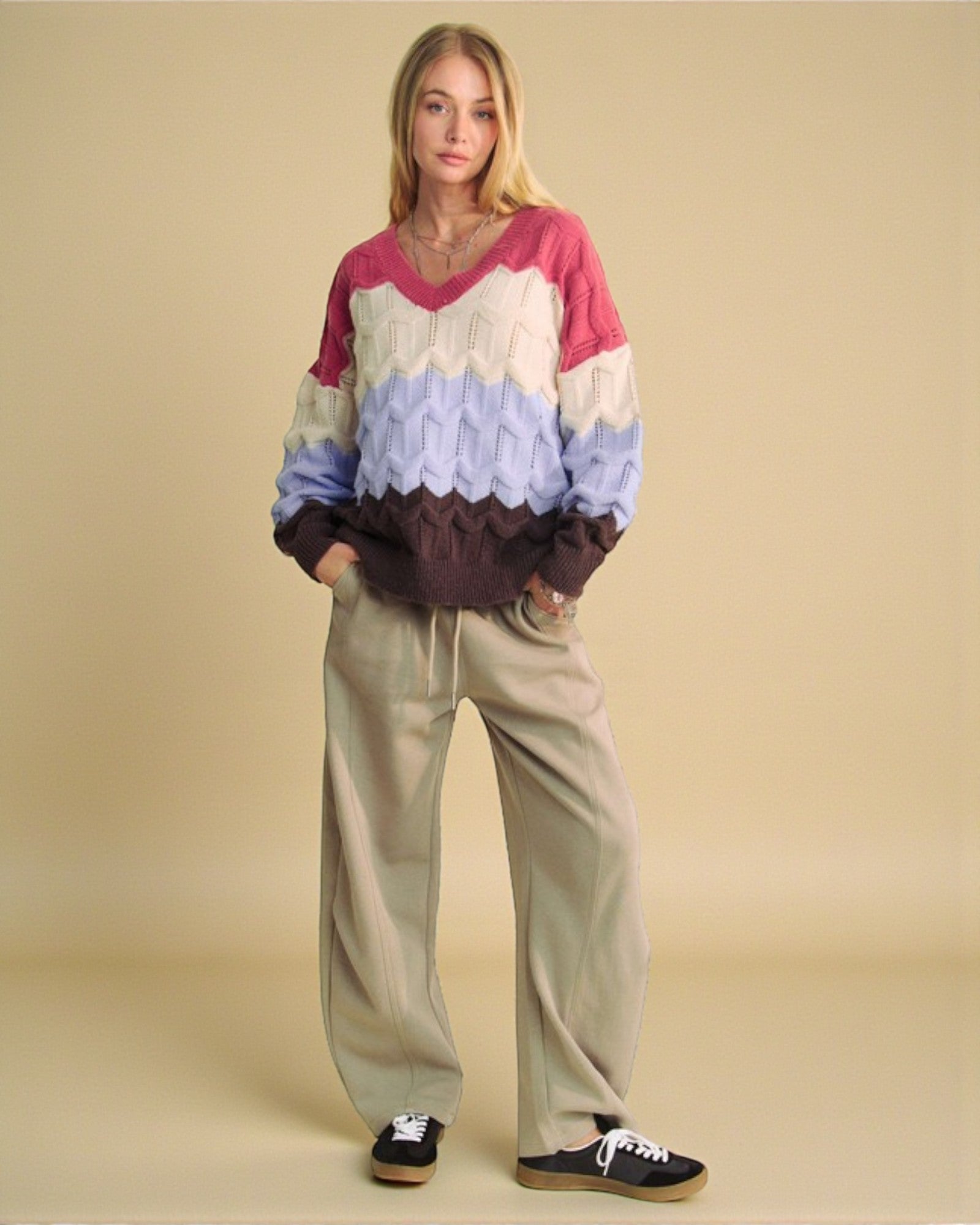 Woman wearing a colorful sweater and beige pants on a beige background
