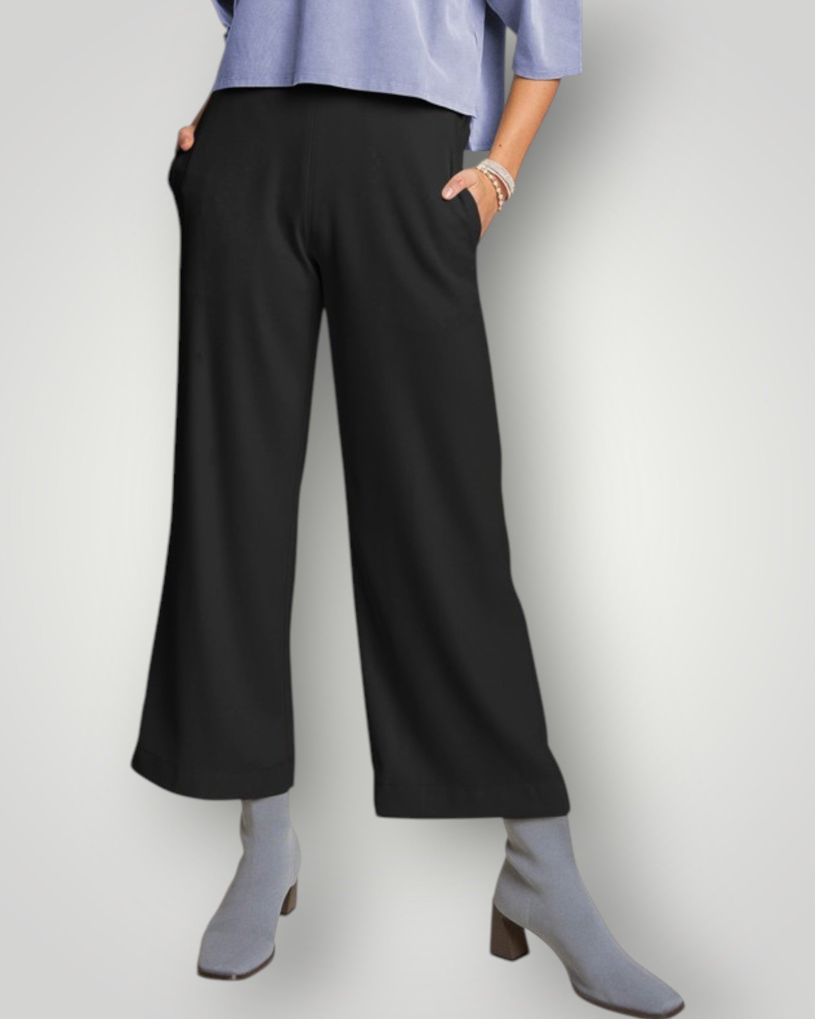 Person wearing black wide-leg pants with a light blue top on a white background