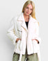 Woman wearing a white fur coat against a plain background