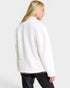 Woman wearing a white sweater against a plain background