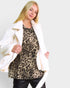 Woman wearing a leopard print top and white coat on a plain background