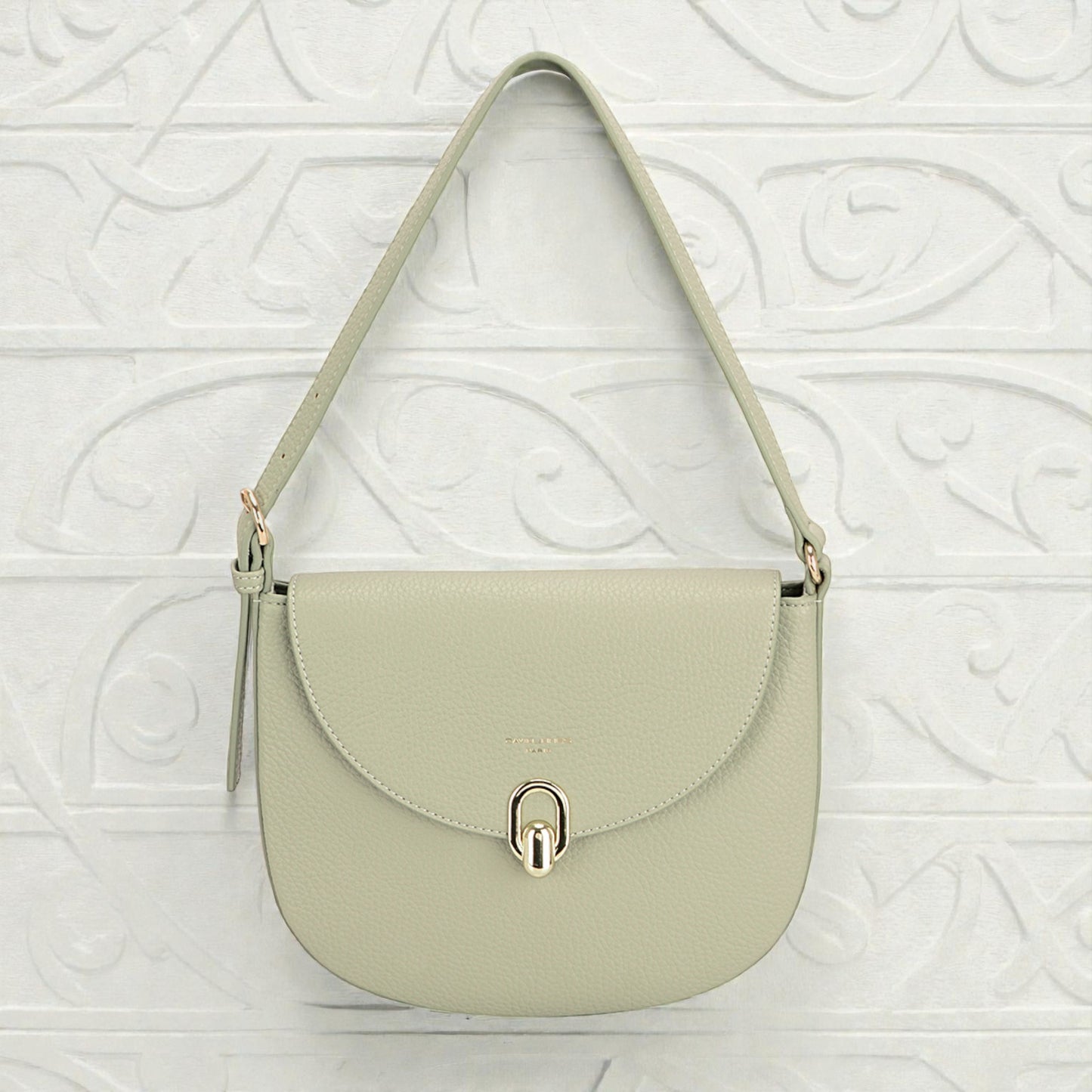 Light green handbag with a gold clasp on a textured white background