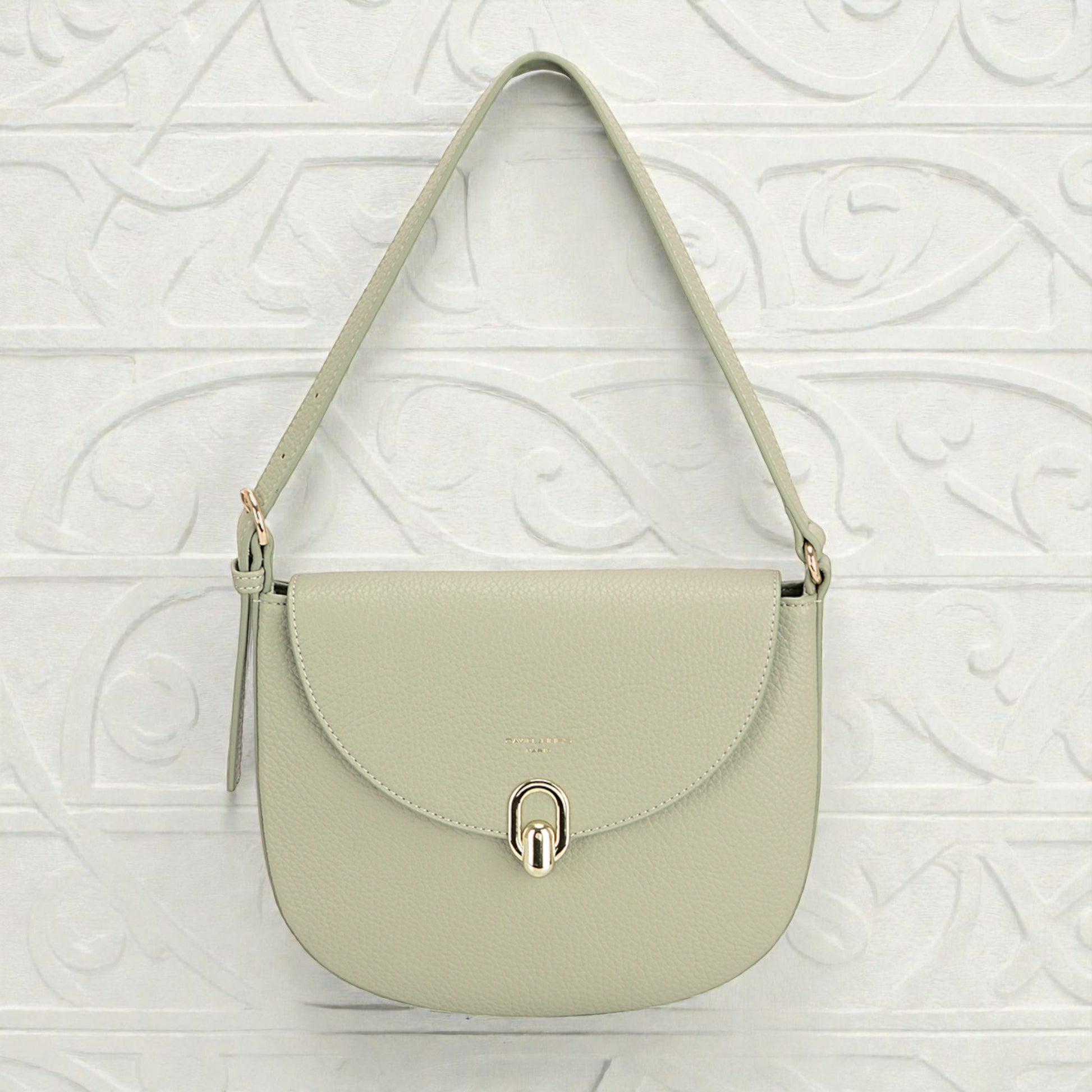 Light green handbag with a gold clasp on a textured white background