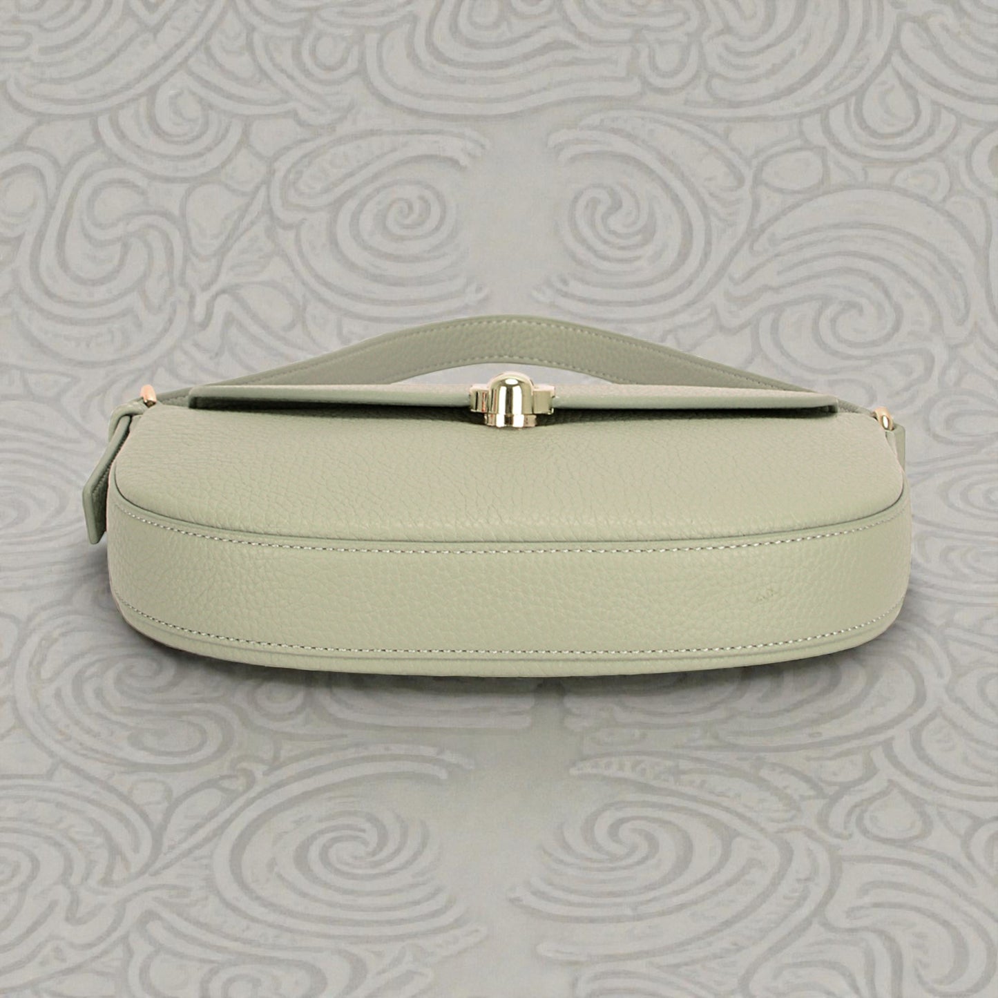 Light green handbag with gold clasp on a gray textured background