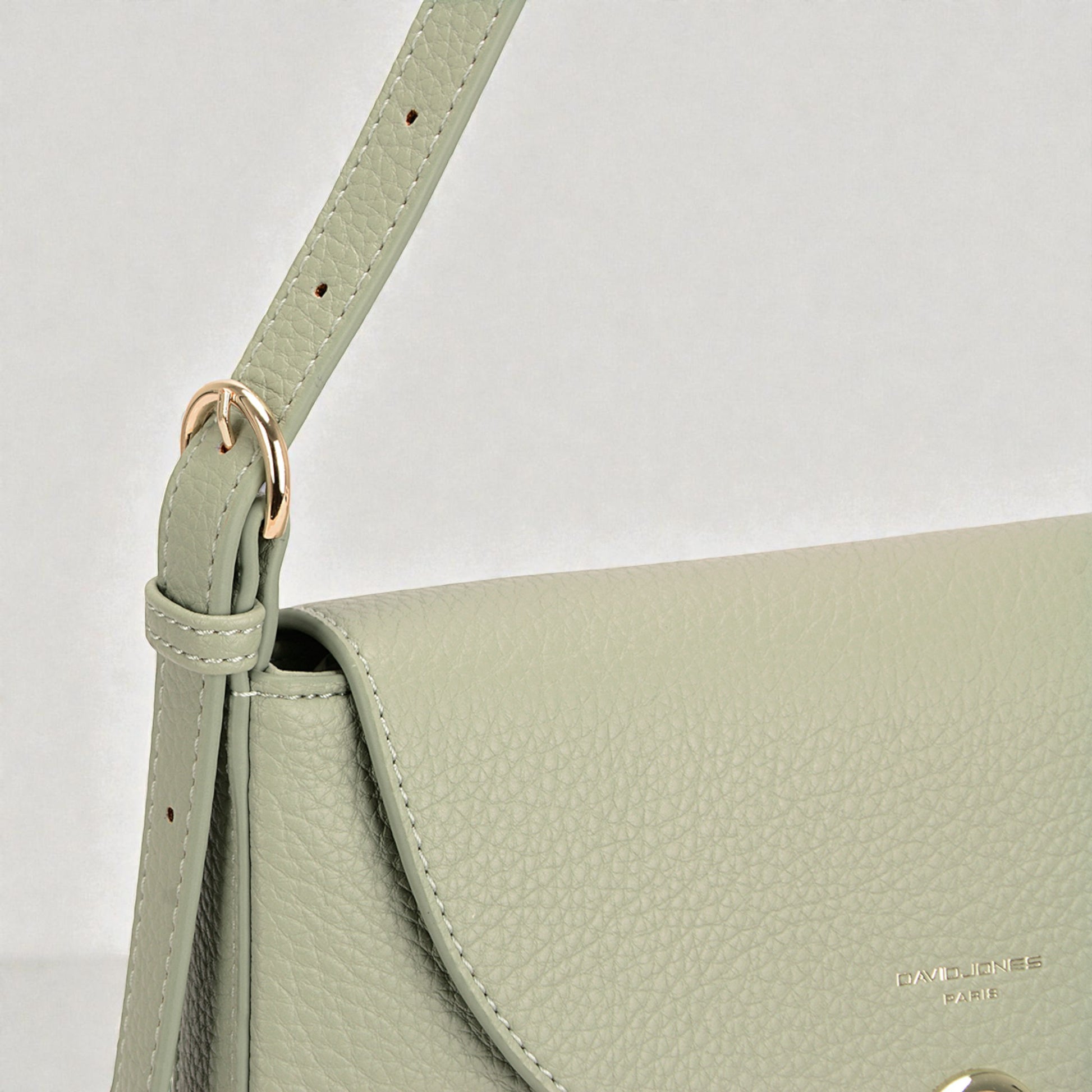 Green handbag with a strap on a light gray background