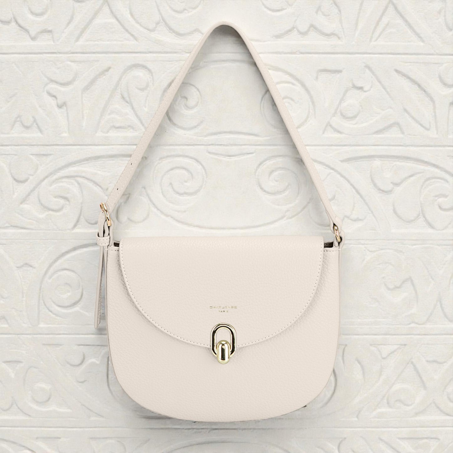 White handbag with a gold lock on a white textured background