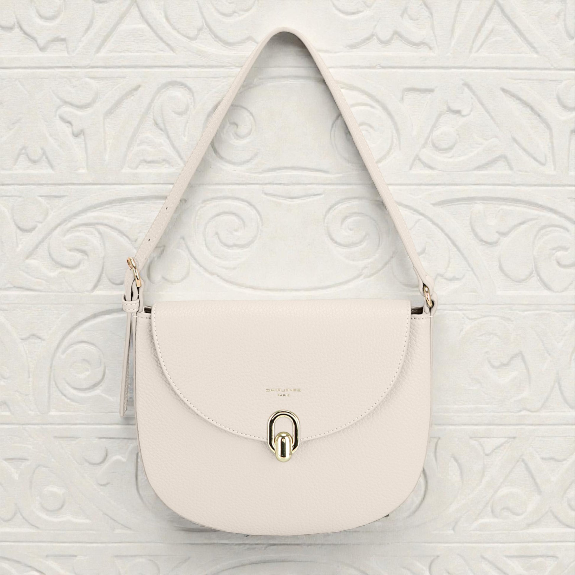 White handbag with a gold lock on a white textured background