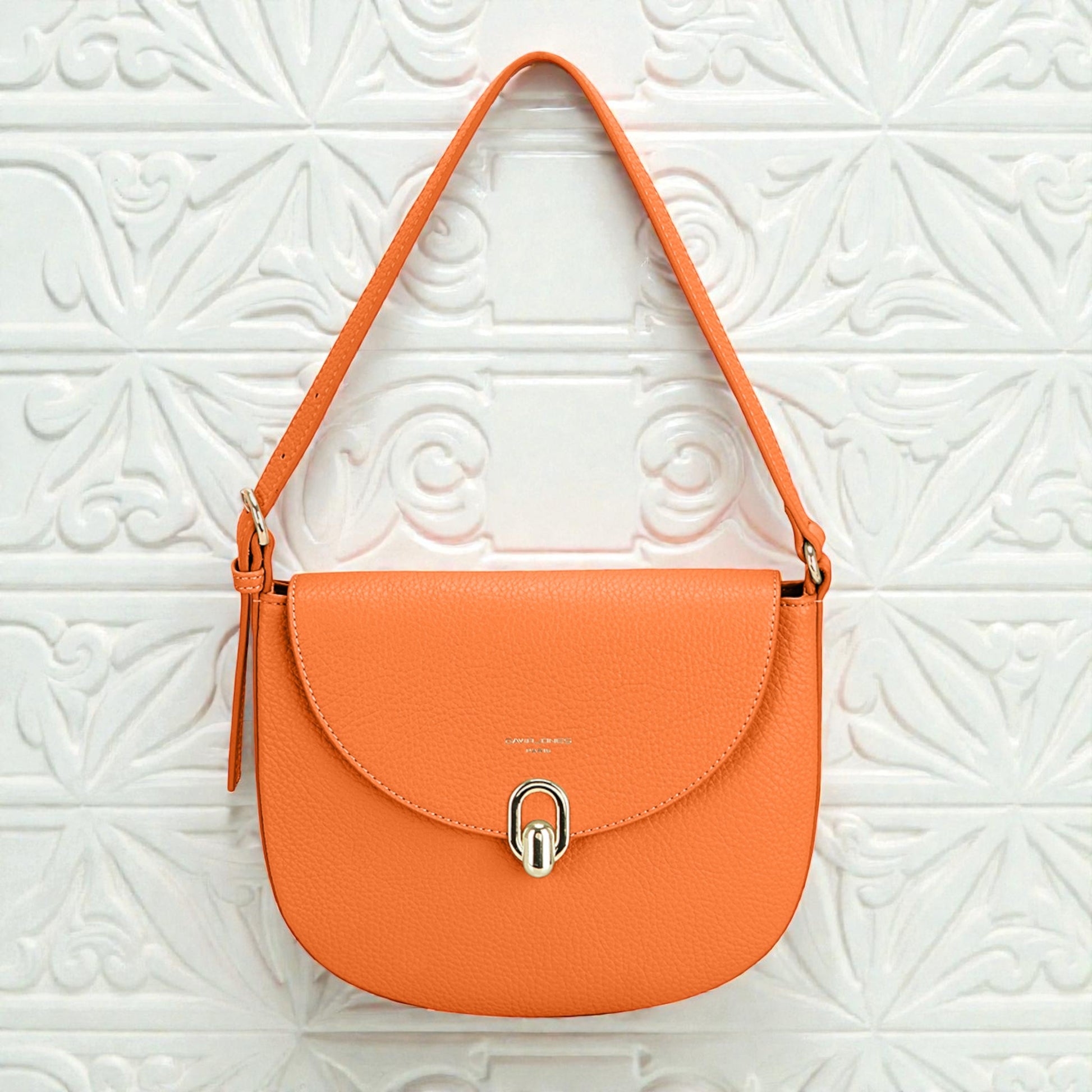 Orange handbag with a silver clasp on a white textured background