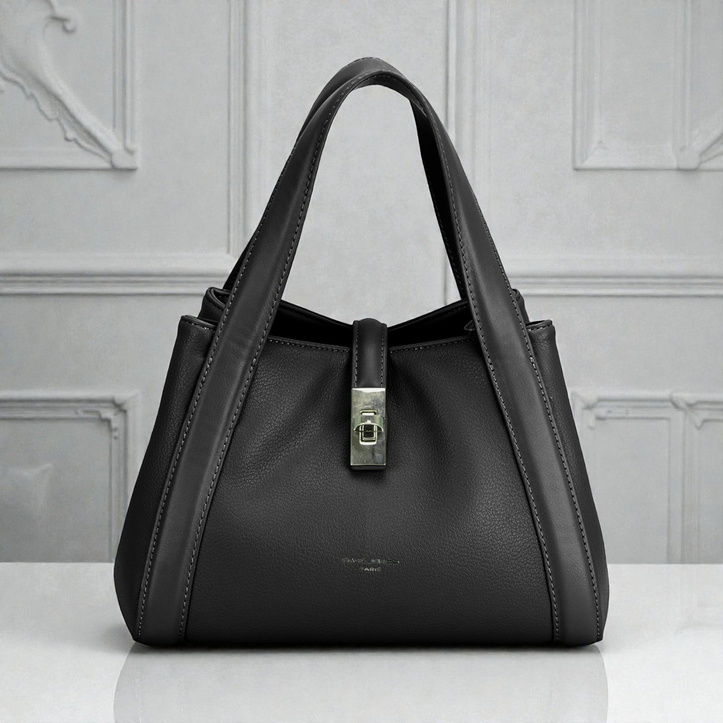 Black handbag with a silver clasp on a light gray background
