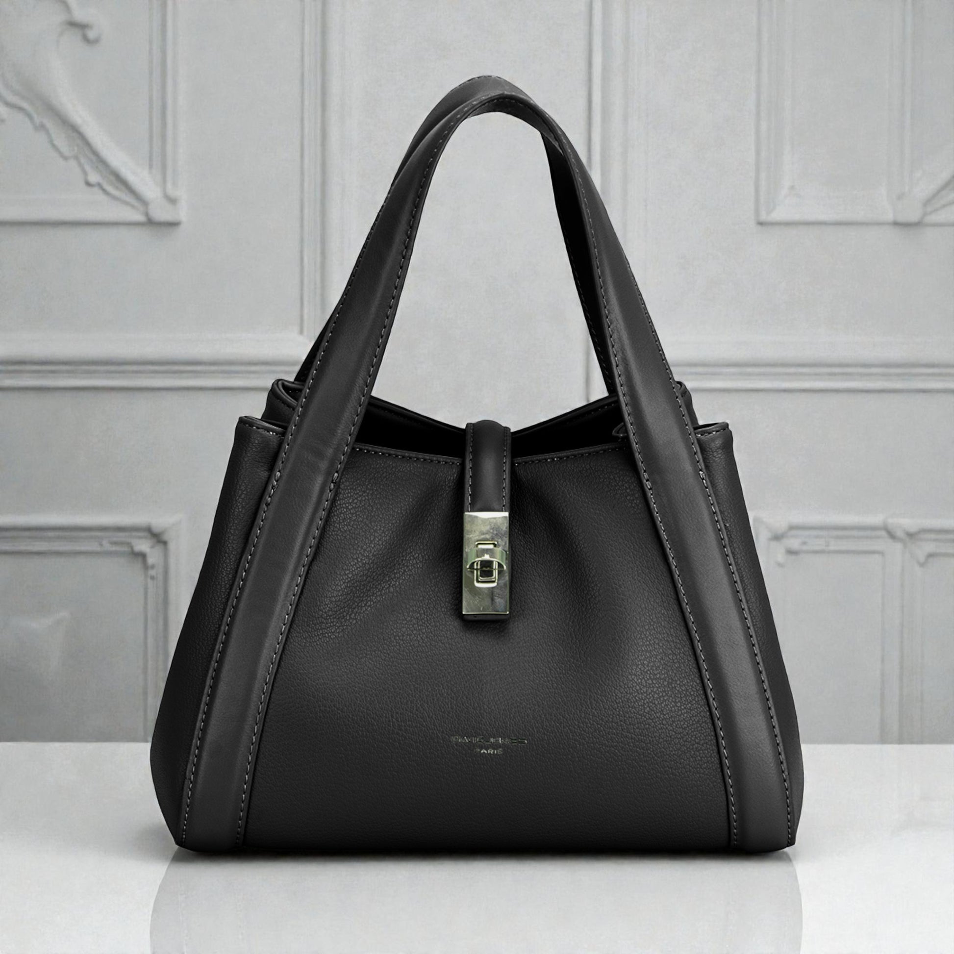 Black handbag with a silver clasp on a light gray background