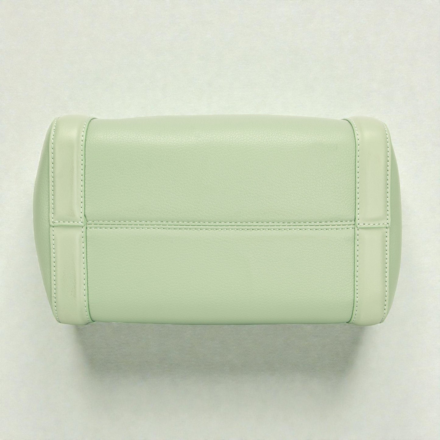 Light green quilted handbag on a light gray background