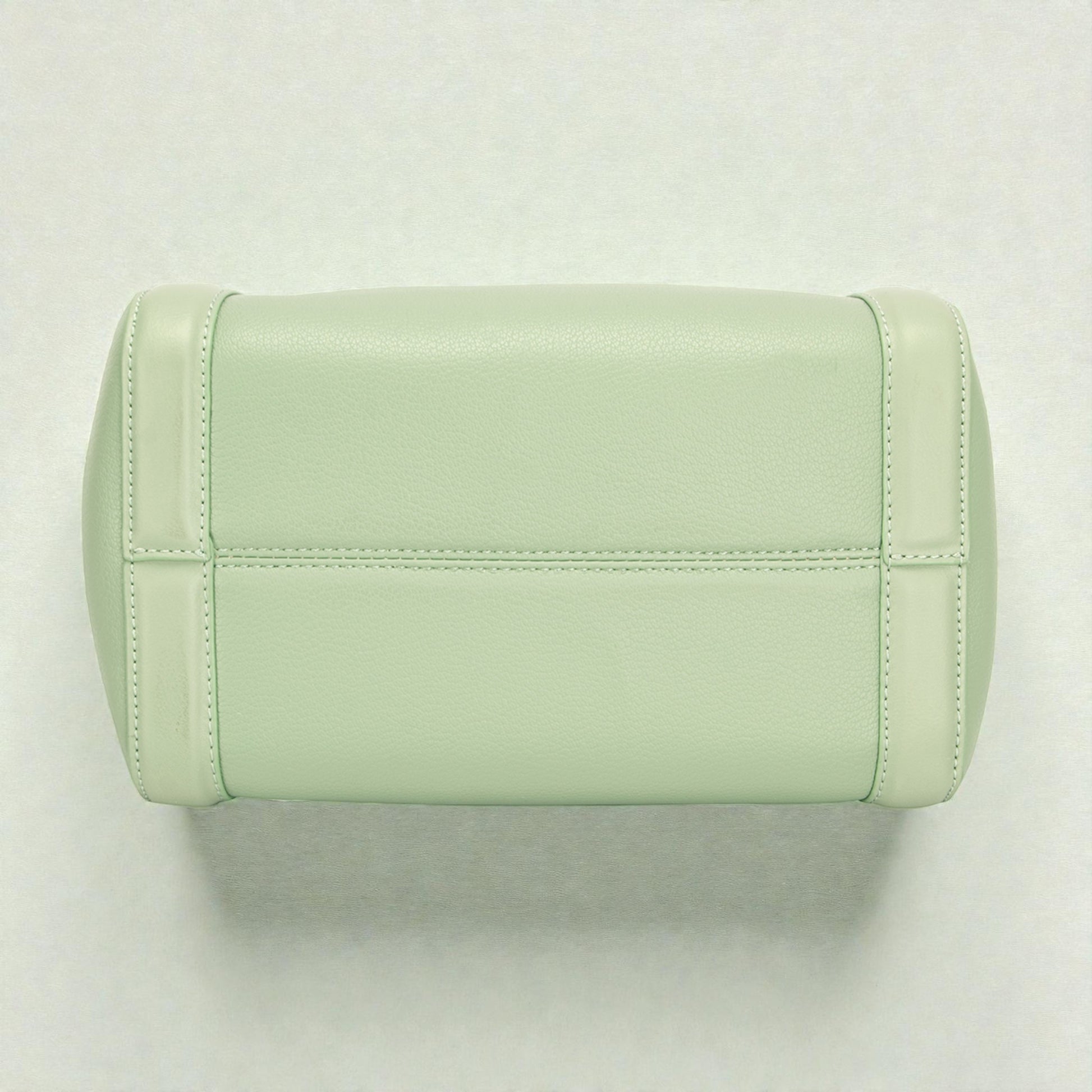 Light green quilted handbag on a light gray background